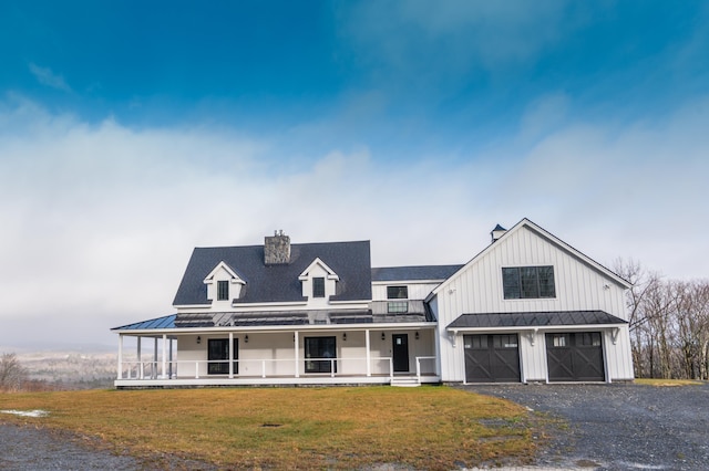 modern farmhouse featuring a porch, a garage, and a front lawn