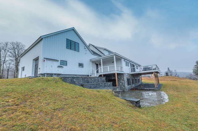 back of property featuring a wooden deck, a yard, and a garage