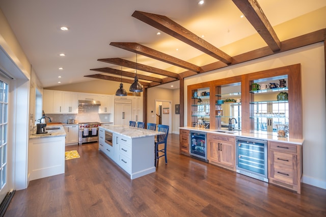 kitchen with white cabinetry, a kitchen island, beverage cooler, and high end range