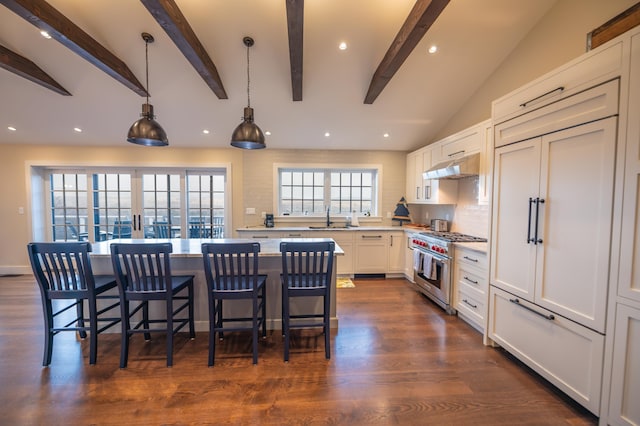 kitchen with premium range, sink, white cabinetry, tasteful backsplash, and decorative light fixtures