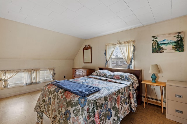 bedroom with vaulted ceiling and a baseboard heating unit