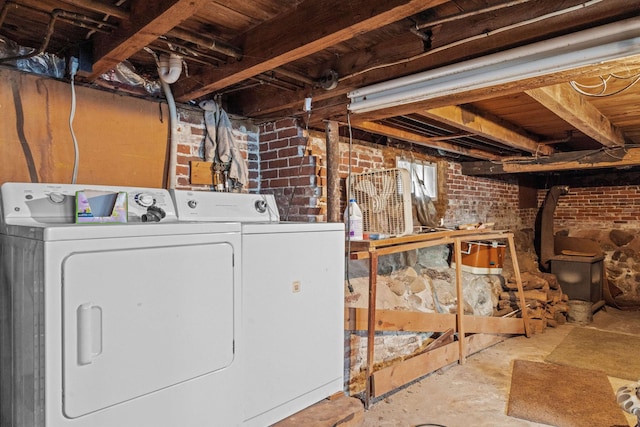 laundry room featuring washer and dryer and brick wall