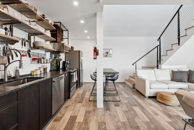 kitchen featuring appliances with stainless steel finishes, light wood-type flooring, dark brown cabinetry, and sink