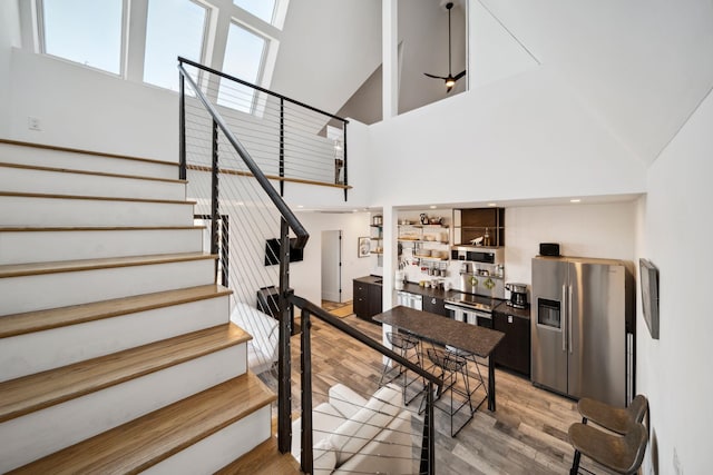 stairs with hardwood / wood-style floors and high vaulted ceiling