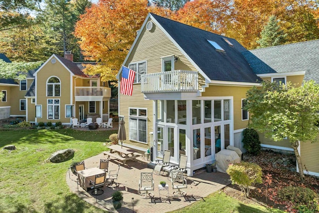 back of house featuring a sunroom, a balcony, a yard, and a patio