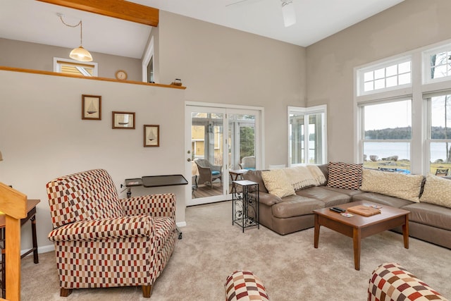 carpeted living room featuring ceiling fan, a water view, and a towering ceiling