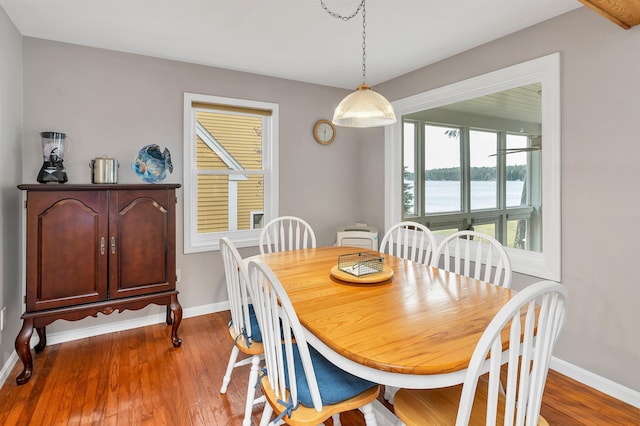 dining room with hardwood / wood-style flooring and a water view