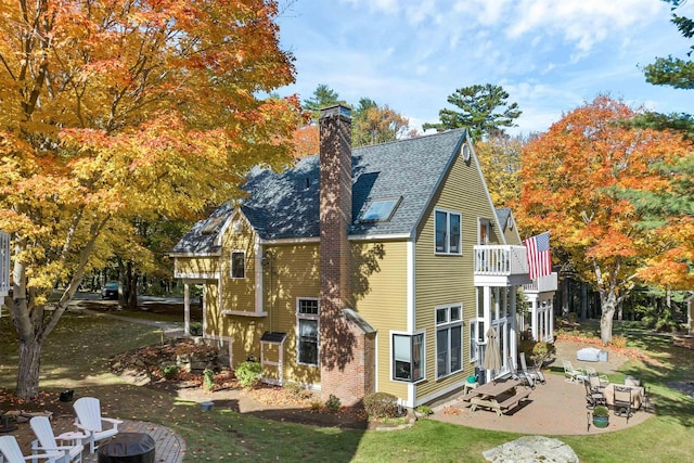 rear view of house featuring a lawn, a patio area, and a balcony