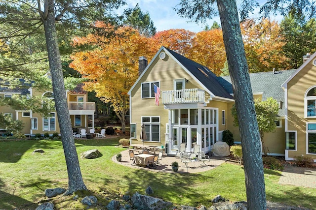 rear view of house featuring a yard, a balcony, and a patio