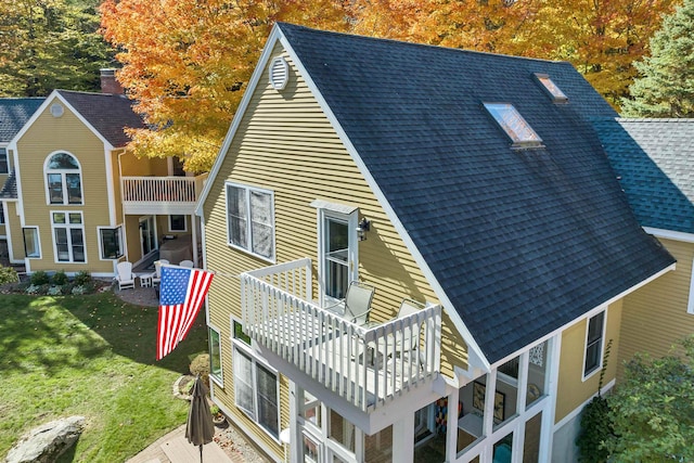 rear view of property with a lawn and a balcony