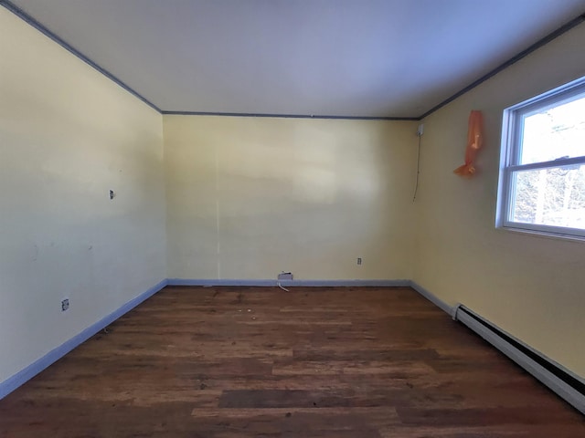 spare room with ornamental molding, baseboard heating, and dark wood-type flooring