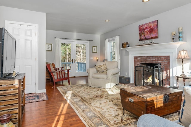 living room with a brick fireplace, dark wood-type flooring, and french doors