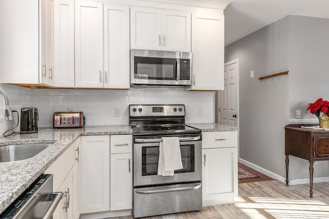 kitchen featuring light stone counters, white cabinetry, sink, and appliances with stainless steel finishes