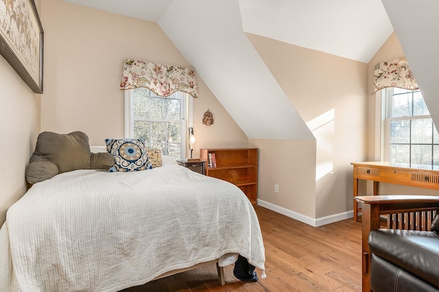 bedroom with light wood-type flooring, multiple windows, and lofted ceiling