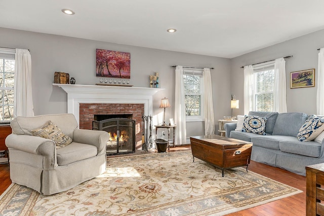 living room featuring wood-type flooring and a brick fireplace