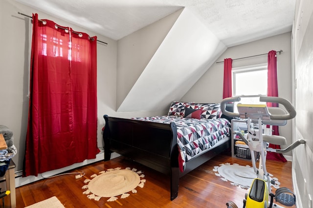 bedroom featuring lofted ceiling, a textured ceiling, and dark wood-type flooring