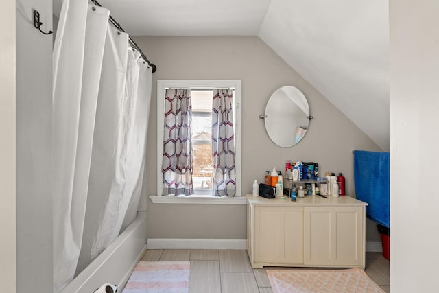 bathroom with shower / tub combo with curtain and lofted ceiling