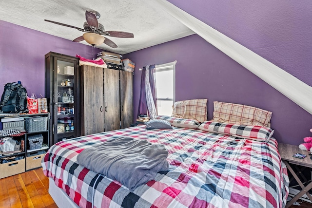 bedroom featuring hardwood / wood-style flooring, ceiling fan, a textured ceiling, and vaulted ceiling