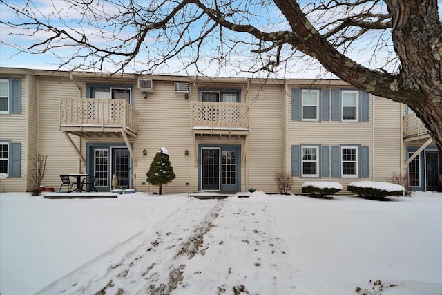 snow covered rear of property with a balcony