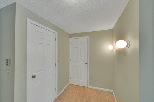 hallway featuring light carpet and a textured ceiling