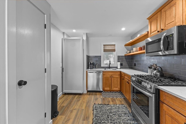 kitchen with decorative backsplash, sink, stainless steel appliances, and light hardwood / wood-style flooring