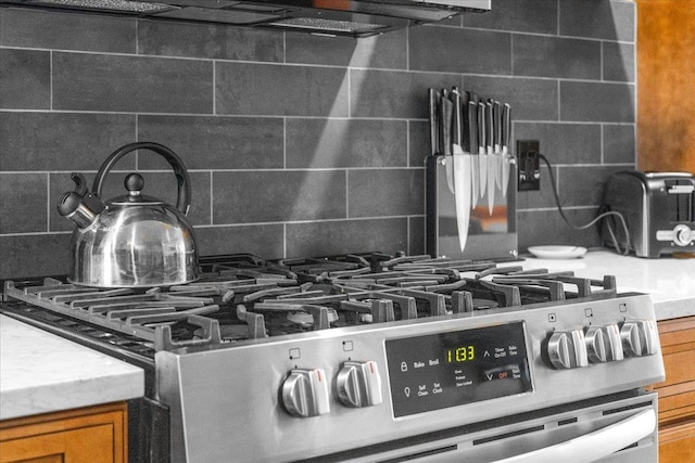 room details featuring gas stove, light stone countertops, and backsplash