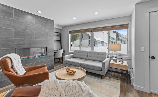 living room with wood-type flooring, a tile fireplace, and a baseboard radiator