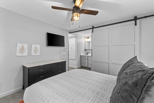 bedroom with ceiling fan, a barn door, carpet floors, and connected bathroom