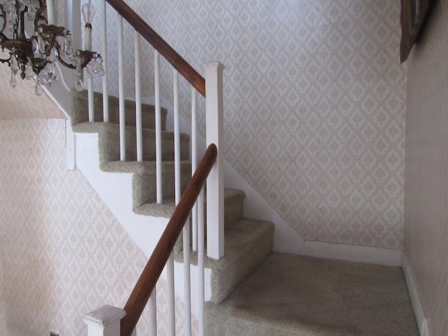 stairway featuring a notable chandelier