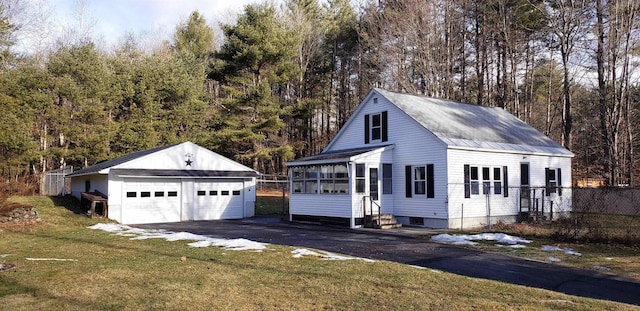 view of front of home with an outbuilding, a sunroom, a garage, and a front yard