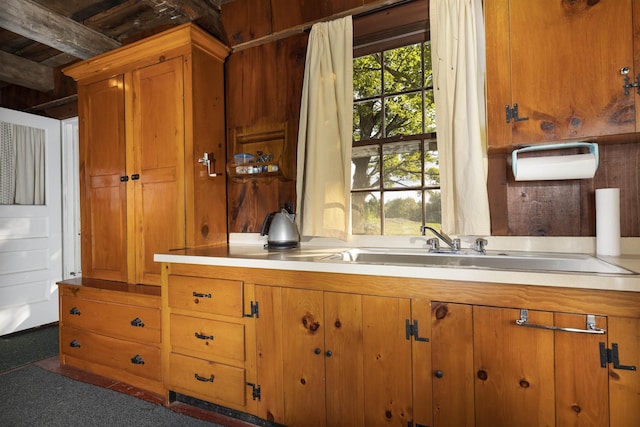 kitchen featuring beam ceiling, dark carpet, and sink