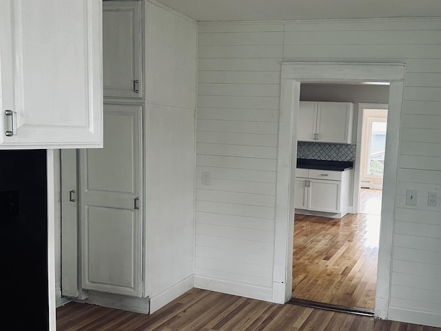 interior space with wooden walls and dark wood-type flooring