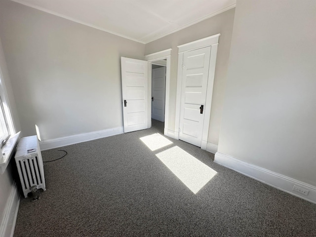 unfurnished bedroom featuring dark carpet, radiator heating unit, and crown molding