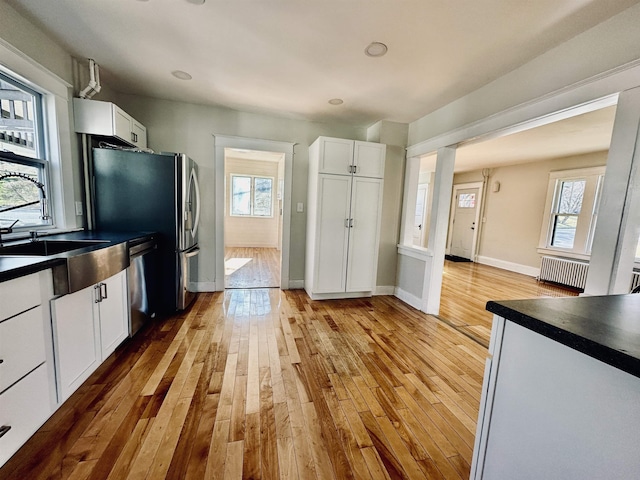 kitchen featuring white cabinets, appliances with stainless steel finishes, wood-type flooring, and sink