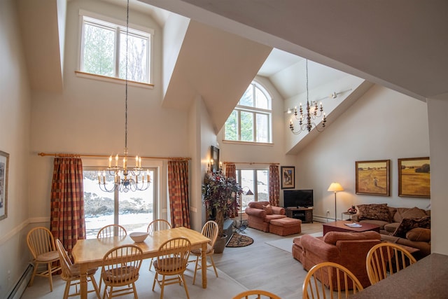 dining space featuring high vaulted ceiling, an inviting chandelier, baseboard heating, and light hardwood / wood-style flooring