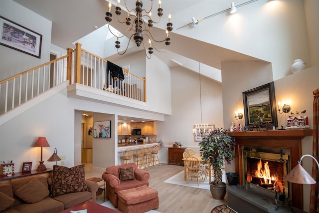 living room featuring high vaulted ceiling, light hardwood / wood-style floors, and an inviting chandelier