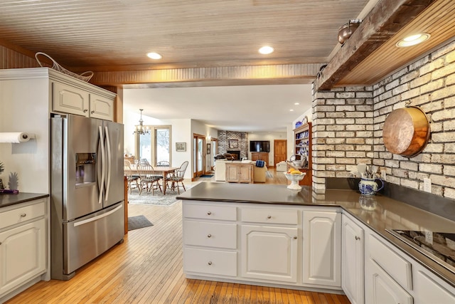 kitchen with kitchen peninsula, stainless steel fridge, white cabinets, and light hardwood / wood-style floors