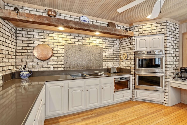 kitchen featuring black electric stovetop, brick wall, stainless steel double oven, light hardwood / wood-style flooring, and white cabinetry