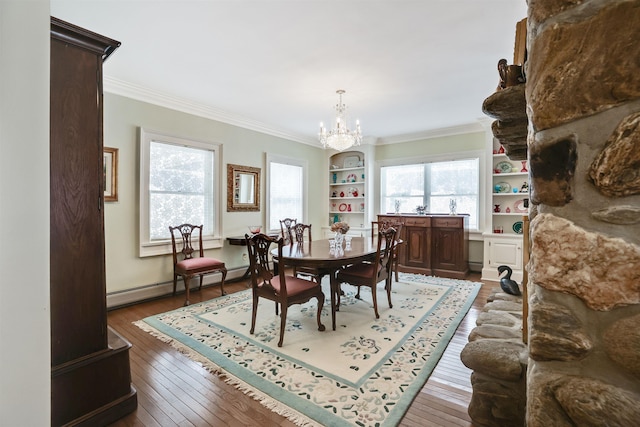 dining area featuring wood-type flooring, baseboard heating, crown molding, and a notable chandelier