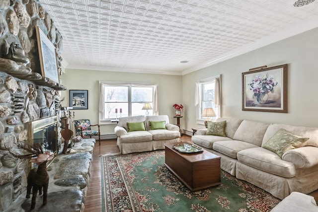 living room with hardwood / wood-style floors, a stone fireplace, ornamental molding, and baseboard heating