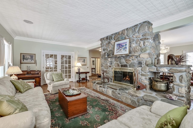 living room featuring a fireplace, french doors, hardwood / wood-style flooring, and crown molding