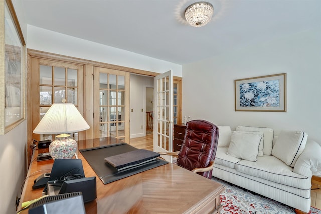 office space with an inviting chandelier, wood-type flooring, and french doors