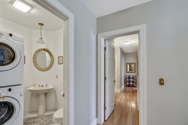 interior space with hardwood / wood-style floors, toilet, and stacked washer and clothes dryer