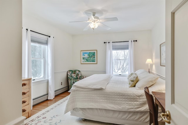 bedroom featuring ceiling fan, a baseboard radiator, and light hardwood / wood-style flooring