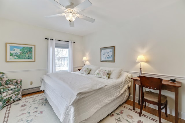 bedroom with light wood-type flooring, a baseboard radiator, and ceiling fan