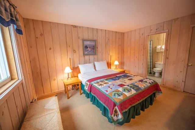 bedroom featuring connected bathroom and wooden walls