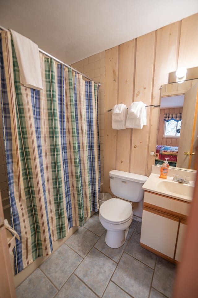 bathroom featuring vanity, toilet, and wood walls