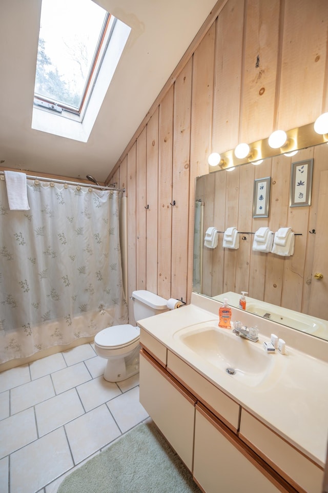 bathroom featuring tile patterned floors, lofted ceiling with skylight, toilet, wooden walls, and vanity