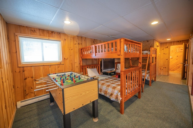 bedroom with carpet, a paneled ceiling, wooden walls, and a baseboard radiator