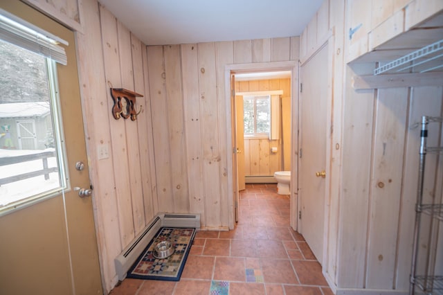 entryway with baseboard heating and wooden walls